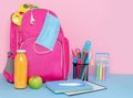 Pink backpack with medical mask, school supplies and lunch of fruit smoothie and apple. Back to school Royalty Free Stock Photo