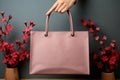 Pink bag, mockup in a woman\'s hand on a background of red flowers vase Royalty Free Stock Photo