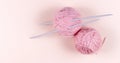 Pink ball of thread for knitting and knitting needles on a light pink background Royalty Free Stock Photo