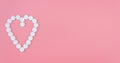 Pink banner with white pills laid out in the shape of a heart. Copy space. Medicines, nutritional supplements, vitamins for