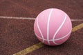 Pink basketball ball on the ground. Close-up ball on the red court.