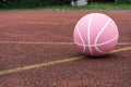 Pink basketball ball on the ground. Close-up ball on the red court.