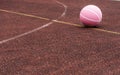 Pink basketball ball on the ground. Close-up ball on the red court. Basketball on the street or indoor court.