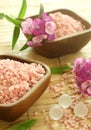 Pink bath salts in wooden bowls and flowers. Royalty Free Stock Photo