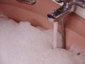 Pink Bathtub Filled to the Brim: Metallic Tap Flows with Water and Abundant Foam Royalty Free Stock Photo