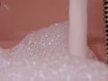 Pink Bathtub Filled to the Brim: Metallic Tap Flows with Water and Abundant Foam Royalty Free Stock Photo