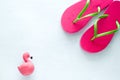 beach flip flops and squishy toy flamingo on white background copy space