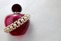 Pink beautiful glass transparent bottle of female perfume decorated with white precious pearls and place for a simple tex