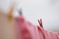 Pink bedding is dried outdoor on a rope with red plastic clothespins. Beautiful selective focus