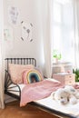 Pink bedding and teddy bear on small kids bed