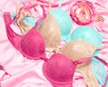 Pink, beige, blue lace bras with perfume on pink silk sheet. Women essentials, female lifestyle concept