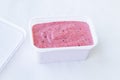 Pink berry ice cream texture in white geometric rectangular square container with open lid, top view. Vegan Blackcurrant