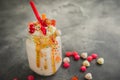 Pink berry milkshake with whipped cream, dripping sauce and candy`s on table Royalty Free Stock Photo