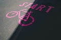 pink bicycle symbol with lettering start painted on inner city asphalt surface. Royalty Free Stock Photo