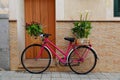 A pink bike with baskets decorated with flowers on the rack and handlebars Royalty Free Stock Photo