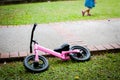 pink little bike for girls parking on the grass and pathway.