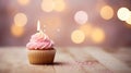 Pink birthday muffin with candle and bokeh lights