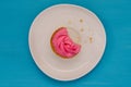 Pink bitten cupcake on a plate isolated on blue background. Delicious cake. Top view Royalty Free Stock Photo