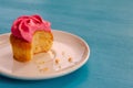 Pink bitten cupcake on a plate isolated on blue background. Delicious cake. Top view Royalty Free Stock Photo