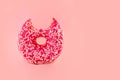 Pink bitten donut on pink pastel background with copy space Royalty Free Stock Photo