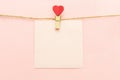 Pink blank paper sheet on a clothes line and clothespegs with red heart on a pink background. Valentines day concept Royalty Free Stock Photo