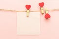 Pink blank paper sheet on a clothes line and clothespegs with red heart on a pink background. Valentines day concept Royalty Free Stock Photo