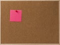 Pink Blank sticky notes red pinned into brown corkboard.