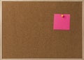 Pink Blank sticky notes yellow pinned into brown corkboard.