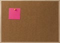 Pink Blank sticky notes yellow pinned into brown corkboard.