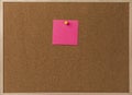 Pink Blank sticky notes yellow pinned into brown corkboard.