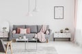 Pink blanket and cushions on grey settee in white flat interior Royalty Free Stock Photo