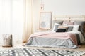 Pink blanket on grey bed in modern bedroom interior with poster