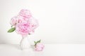 Pink blooming peony flowers in a white vase in a white still-life interior Royalty Free Stock Photo