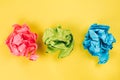 Pink, blue and green crumpled paper balls on bright yellow background Royalty Free Stock Photo