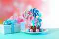 Pink and blue novelty cupcake decorated with candy and large lollipops.