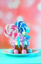 Pink and blue novelty cupcake decorated with candy and large lollipops.