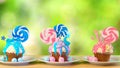 Pink and blue novelty cupcakes decorated with lollipop against garden background