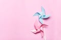 Pink blue paper spinners on light pink background. Kids toys colorful pinwheels on celebration party background. Top view, flat Royalty Free Stock Photo