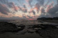 Pink sunset on the beach in Creta, Greece. Beach with blacks rocks and waves at dusk Royalty Free Stock Photo