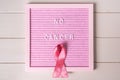 Pink board with the inscription no cancer with a pink ribbon on a white wooden background