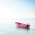 Pink boat floating on calm waters under a blue sky on white background Royalty Free Stock Photo