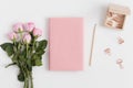 Pink book mockup with a bouquet of pink roses and workspace accessories on a white table