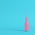 Pink bottle with straw on bright blue background in pastel color