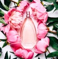 Pink bottle of women`s perfume next to the flowers of peony. Spring gentle fragrance for women. Top view, flat lay Royalty Free Stock Photo