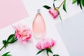 Pink bottle of women`s perfume and peony flowers on white background. Spring gentle fragrance for women. Top view, flat Royalty Free Stock Photo