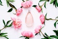 Pink bottle of women`s perfume and peony flowers on white background. Spring gentle fragrance for women. Top view, flat Royalty Free Stock Photo