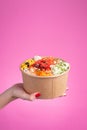 a pink bottom salad poke held by a woman hand with red nails, hawaiian asian food, chopsticks, carrot, green beans, pineapple, soy Royalty Free Stock Photo