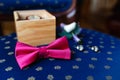 Pink bow tie, beautiful glass cufflinks, flower boutonniere. A men's set of accessories on an old wooden chair with a soft blue s Royalty Free Stock Photo