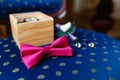 Pink bow tie, beautiful glass cufflinks, flower boutonniere. A men's set of accessories on an old wooden chair with a soft blue s Royalty Free Stock Photo