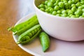 Pink bowl with green peas and three pea pods lie near Royalty Free Stock Photo
